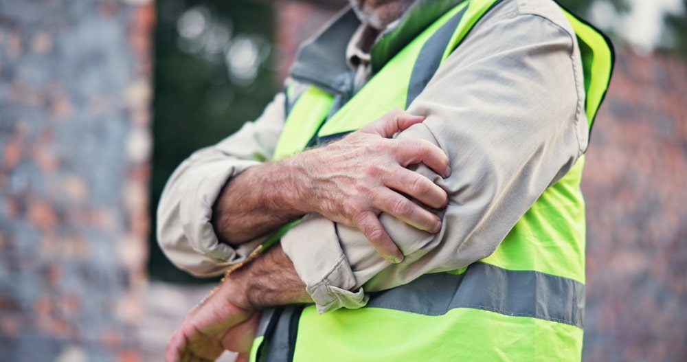 Construction worker in Dallas holding an injured arm after a job site accident.