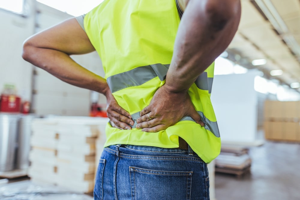 Construction worker experiencing lower back pain after a workplace accident in Dallas. 